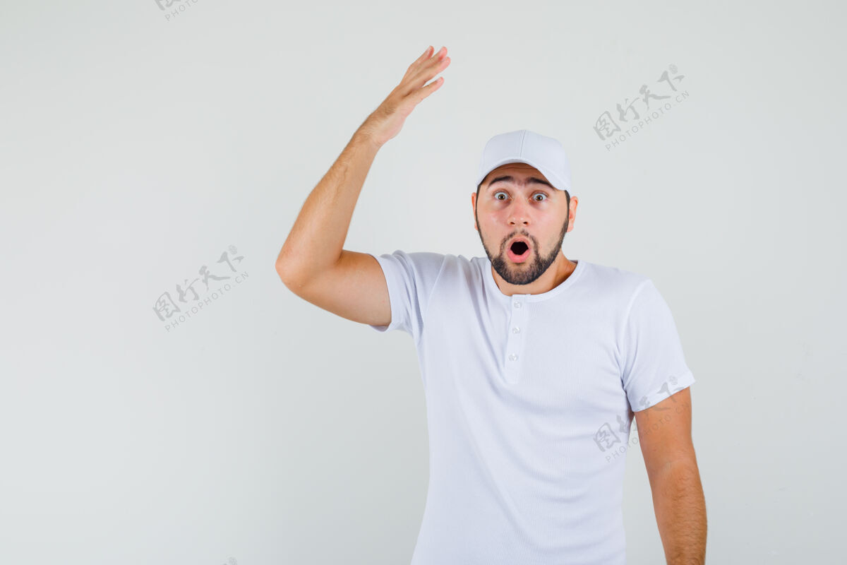 表情穿着白色t恤的年轻人张开手掌举起手臂 看上去很惊讶正视图帽子男性男人