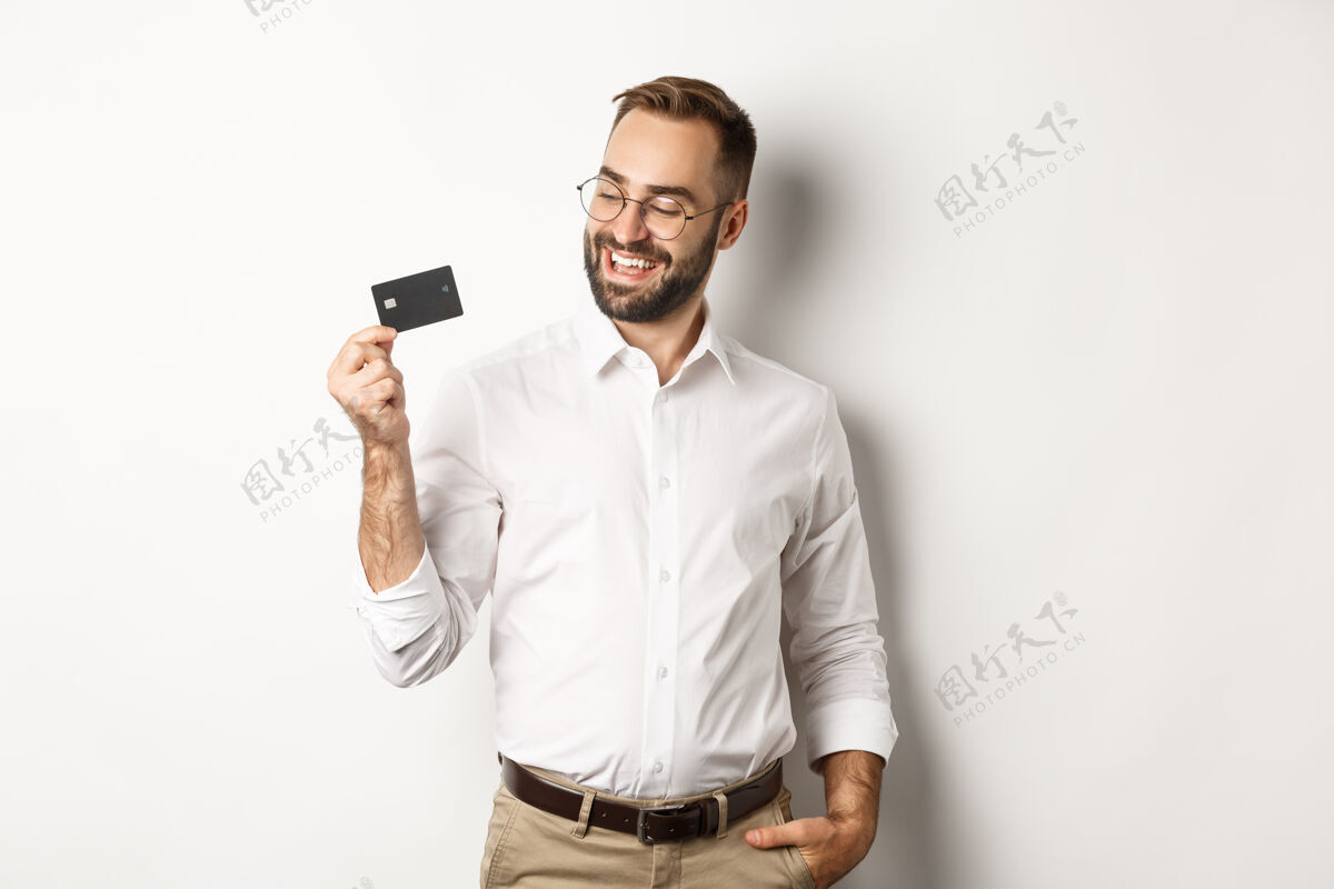 时髦英俊的商人出示他的信用卡 看起来很满意 站着买家信用卡商人