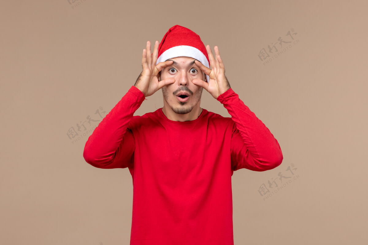 快乐正面图年轻男子睁开眼睛对棕色背景感慨圣诞假期帽子眼睛节日