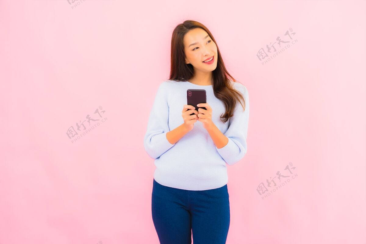 孩子肖像美丽的亚洲年轻女子在粉色隔离墙上使用智能手机女人聪明手机
