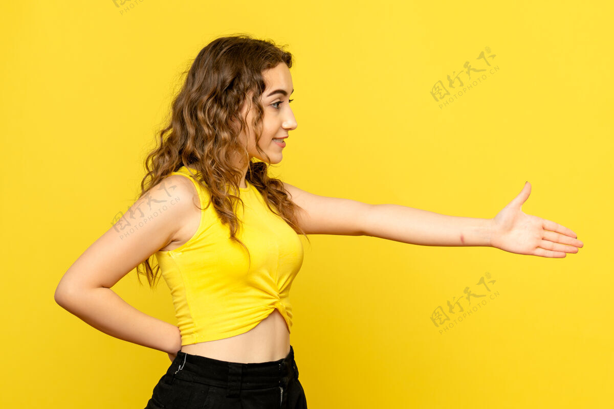 可爱年轻女子试图在黄色墙上握手的正面图漂亮成人尝试