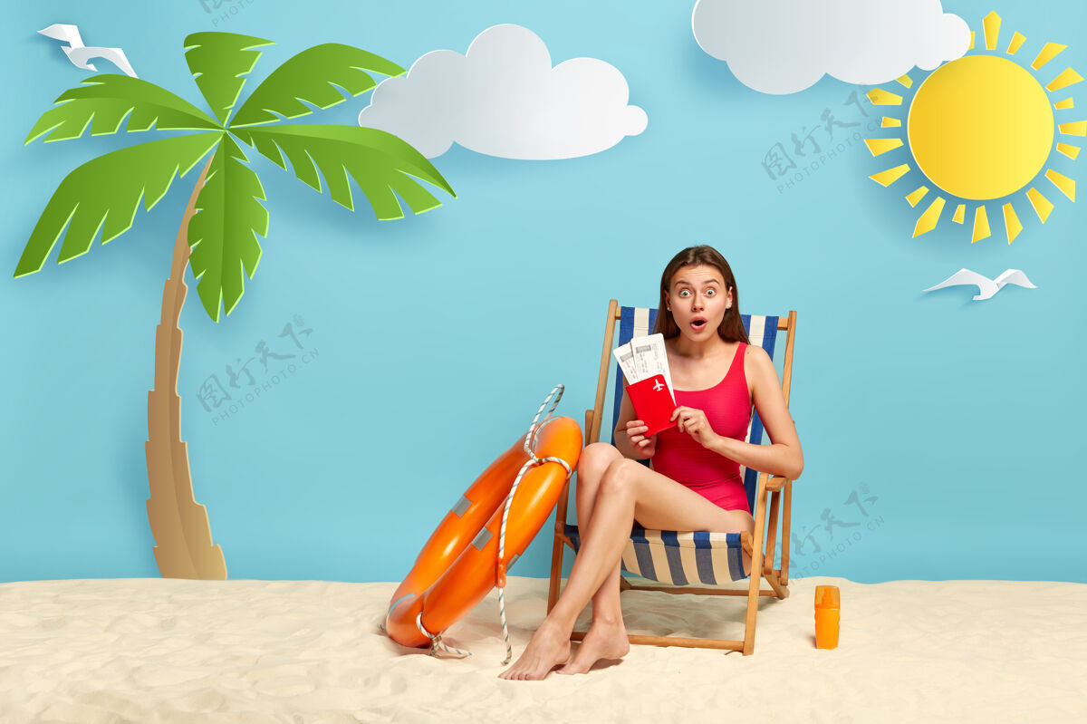 苗条尴尬可爱的女人拿着机票和护照 在沙滩椅上摆姿势 在海上有一次愉快的旅行 穿着泳装奇迹棕榈树自然