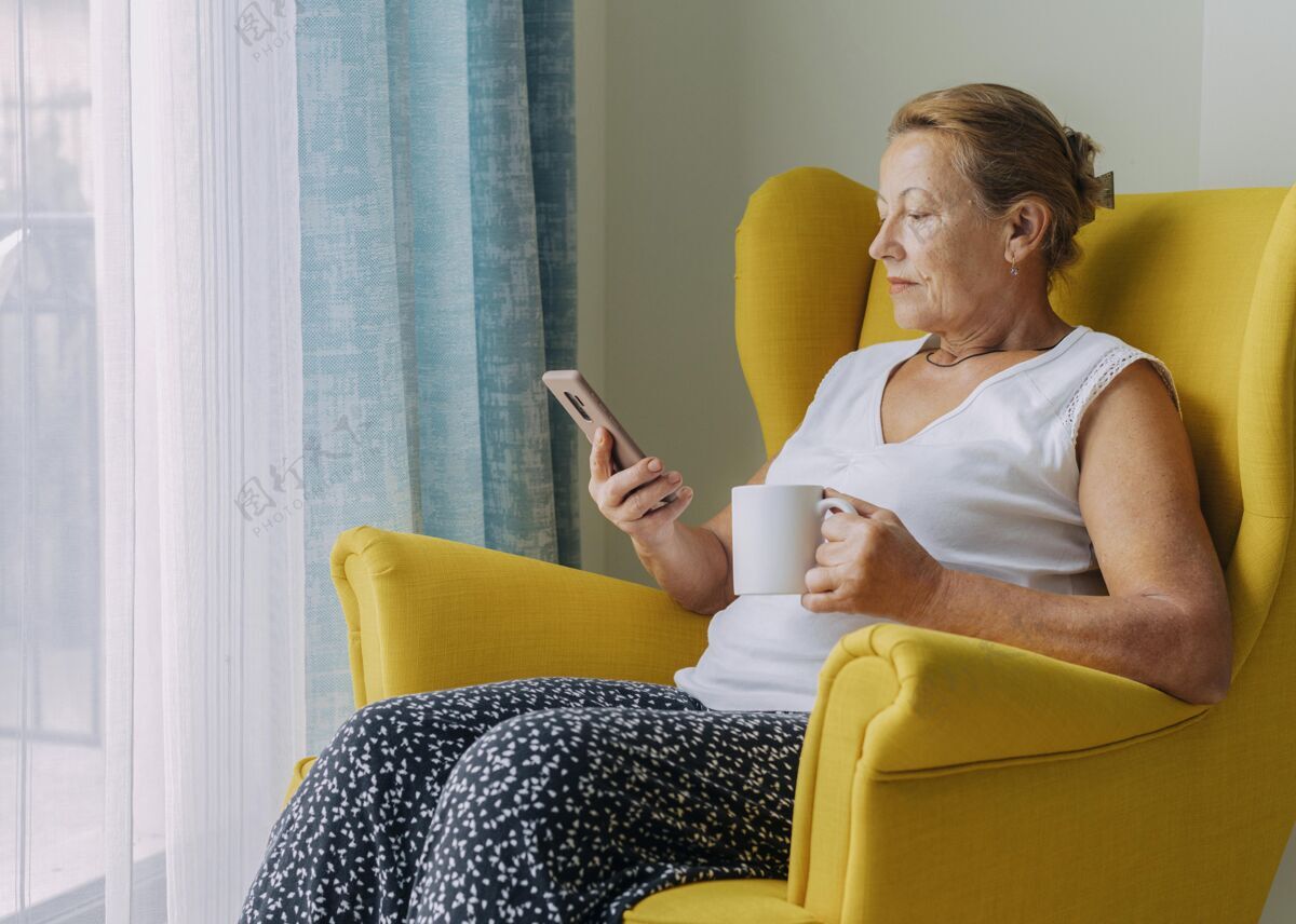 隔离大流行期间 一位老妇人在家喝咖啡时使用智能手机复制流行病冠状病毒