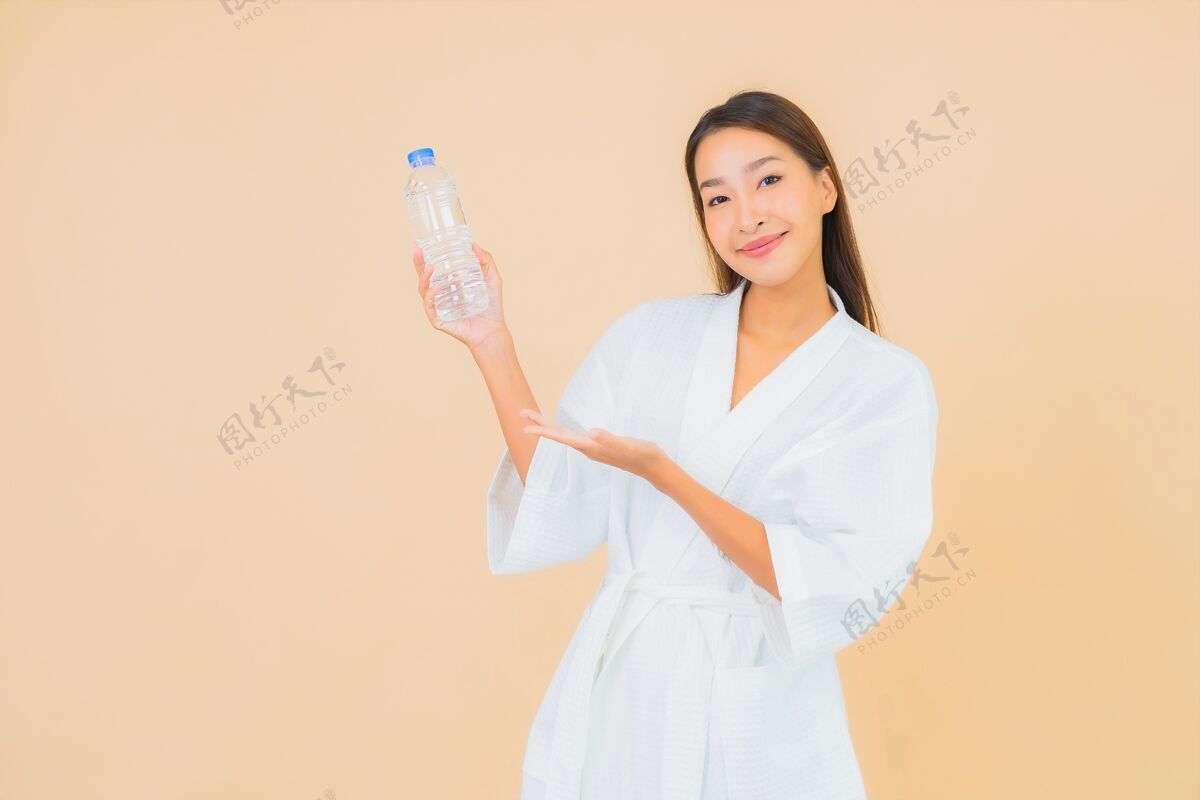健康肖像美丽的亚洲年轻女子与瓶装水喝米色瓶子粉色女人