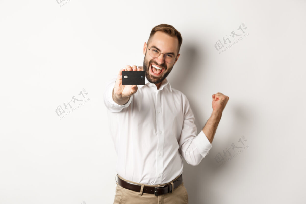 衬衫满意的商人展示信用卡的形象 使拳头泵在欢欣鼓舞 站着信用买家男人