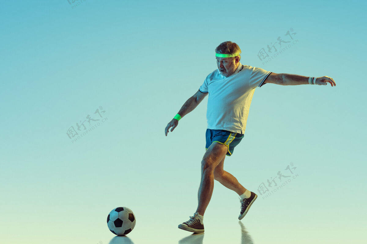 高级穿运动服在斜坡和霓虹灯下踢球的老人球员网球男
