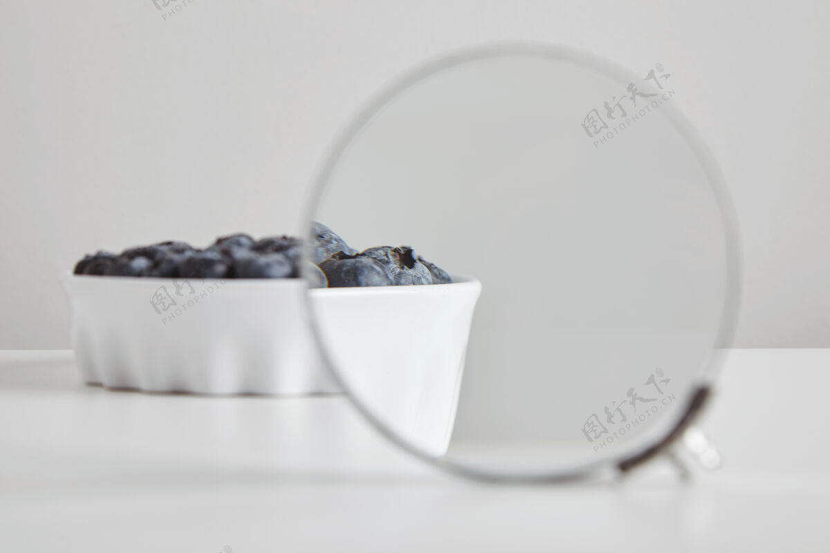 早餐堆蓝莓抗氧化有机超级食品在陶瓷碗的概念健康饮食和营养隔离在白色的桌子上 通过放大镜放大看细节饮食覆盆子食物