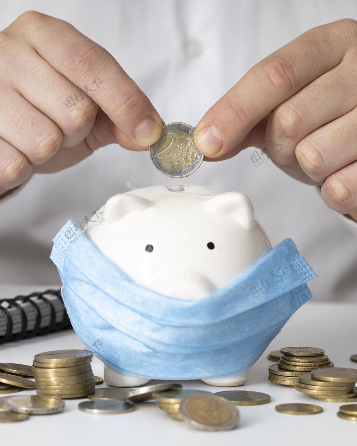 经济一个戴着医用面具的人把一枚硬币塞进了一个存钱罐富有面具安排