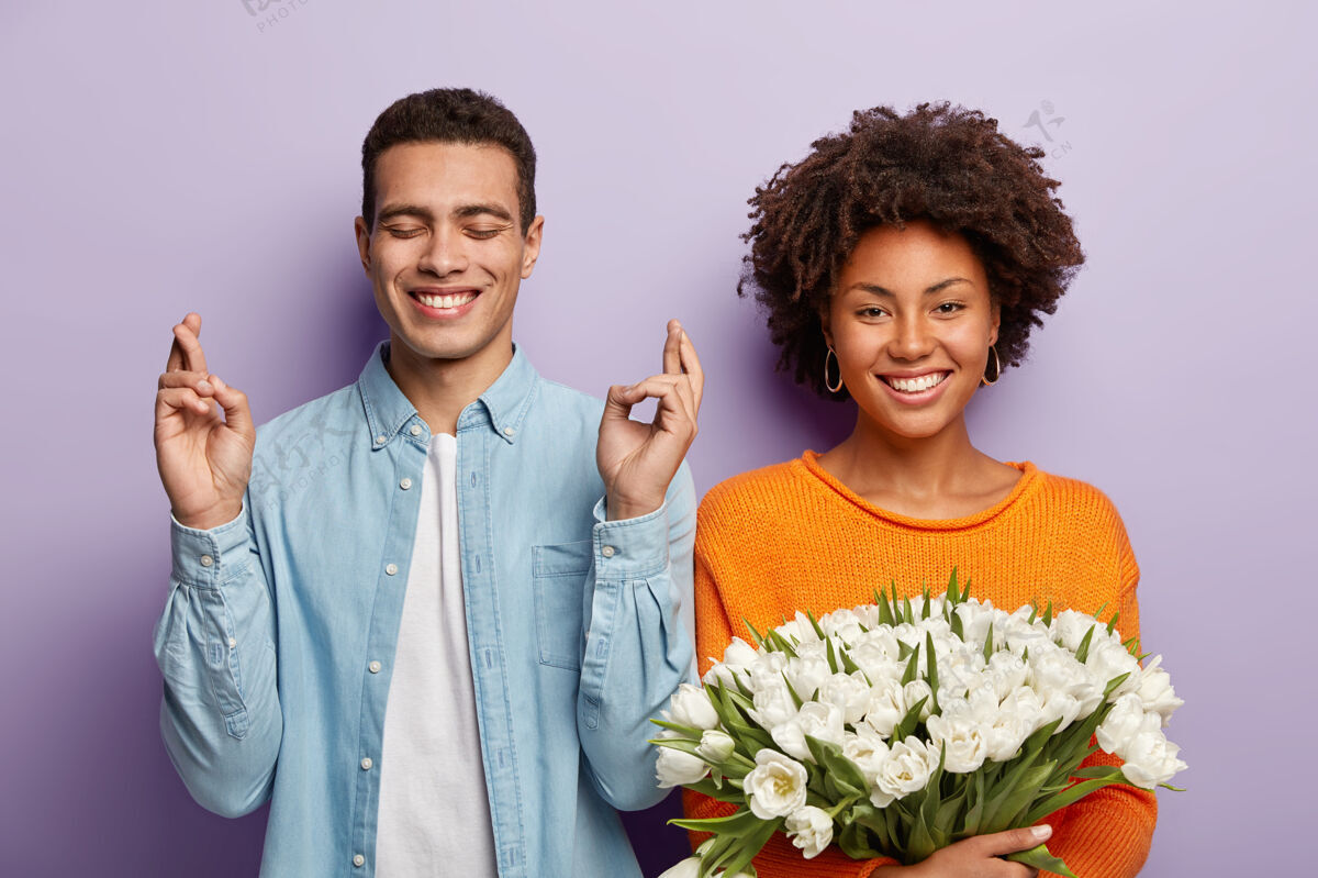 微笑很高兴年轻的男朋友祈祷 希望女朋友同意他的求婚 送上白花混血儿有约会非洲发型的美女捧着一束郁金香祝贺约会丈夫