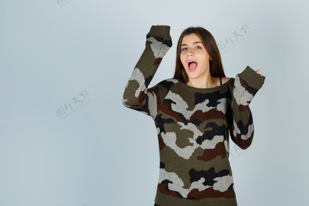 人穿着毛衣的年轻女士举手投降 看上去很有趣毛衣手势年轻