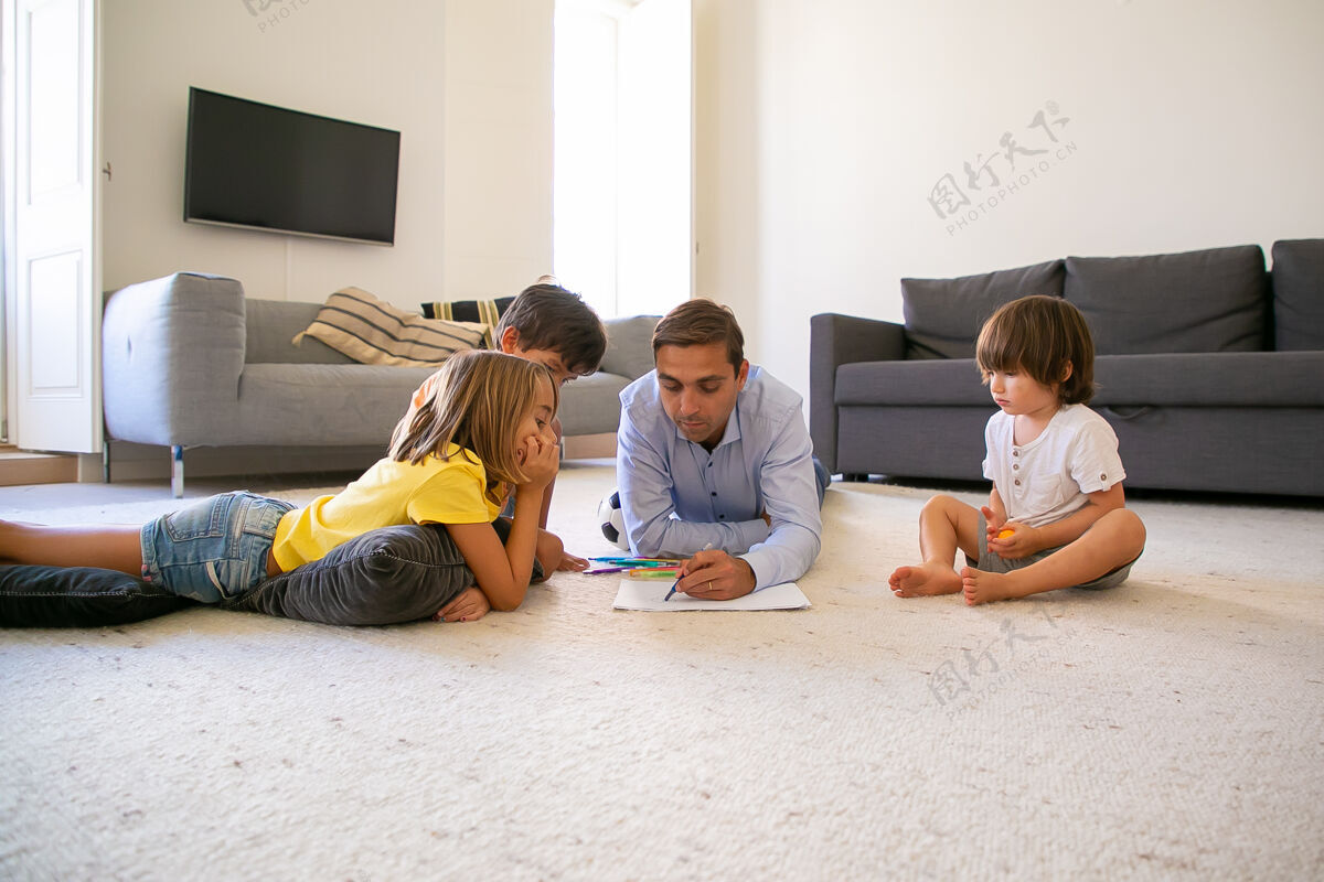 生活专注的爸爸和孩子躺在地毯上 在纸上画画热爱白种人的爸爸用马克笔画画 在家里和可爱的孩子玩耍童年 游戏活动和父亲的概念沙发活动枕头