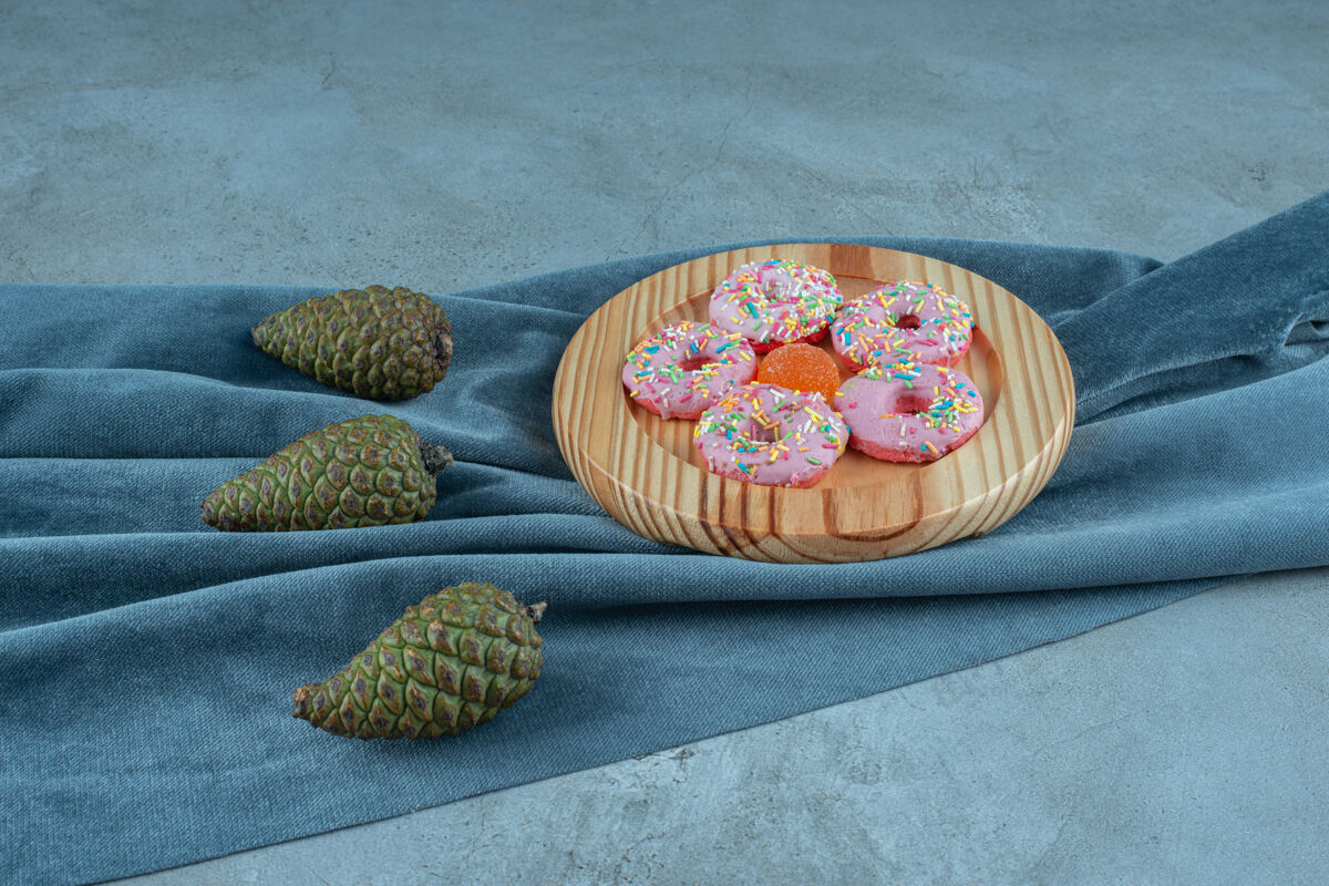 美味松果下面是一块布料 纺织品上是一盘甜甜圈拼盘美味糕点