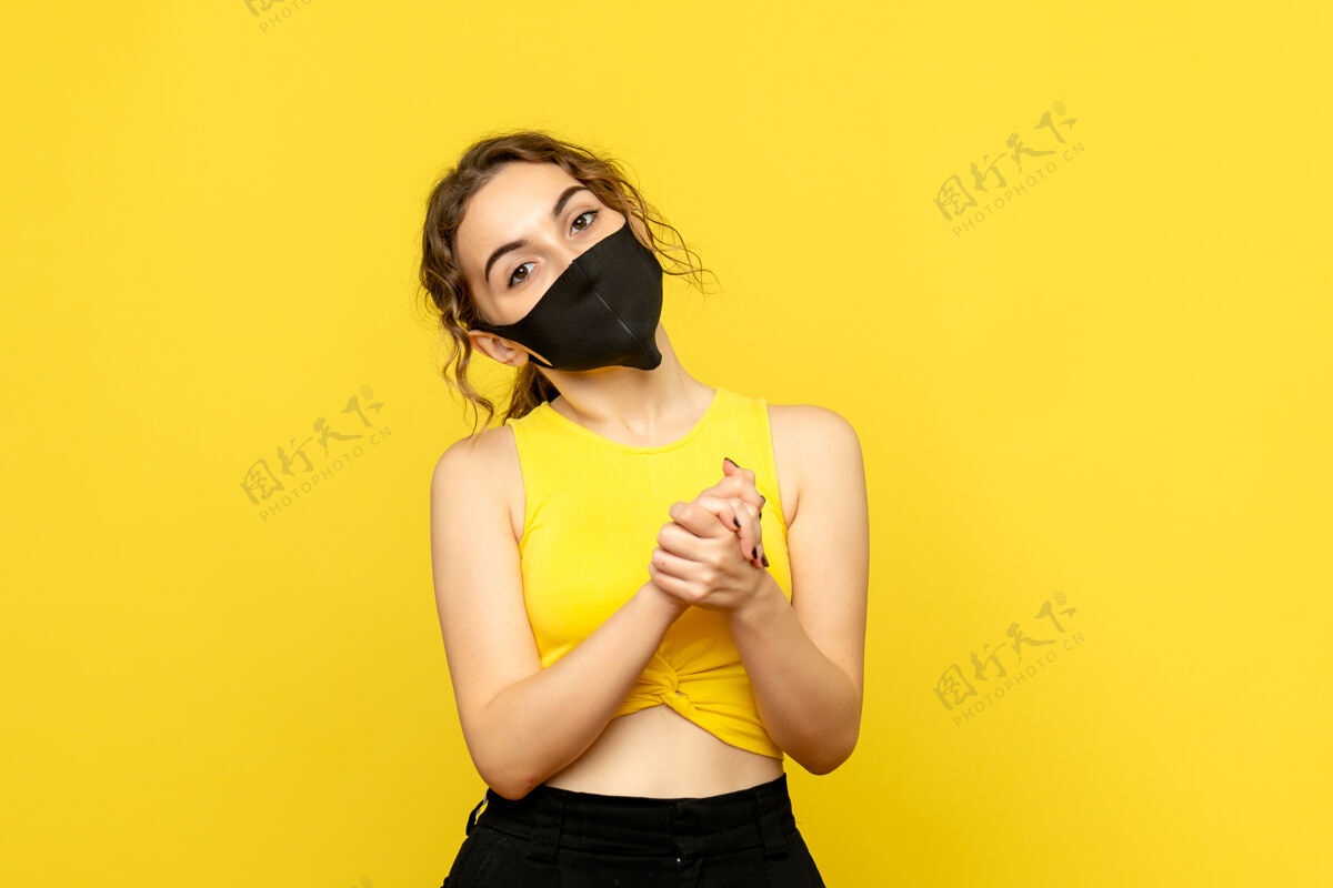 光浅黄色墙上戴着黑色面具的年轻女子的正视图情感头发面具