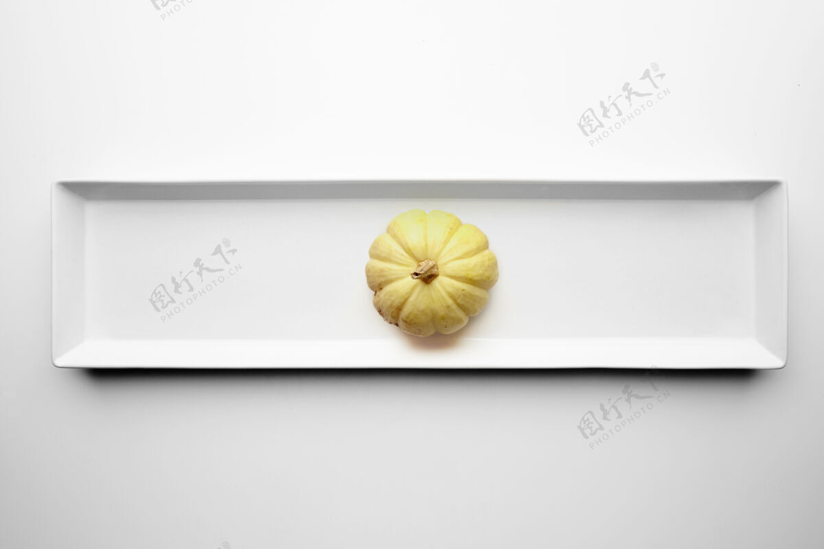自然黄色南瓜孤立在白色背景上的陶瓷矩形板的中心吃生的生活