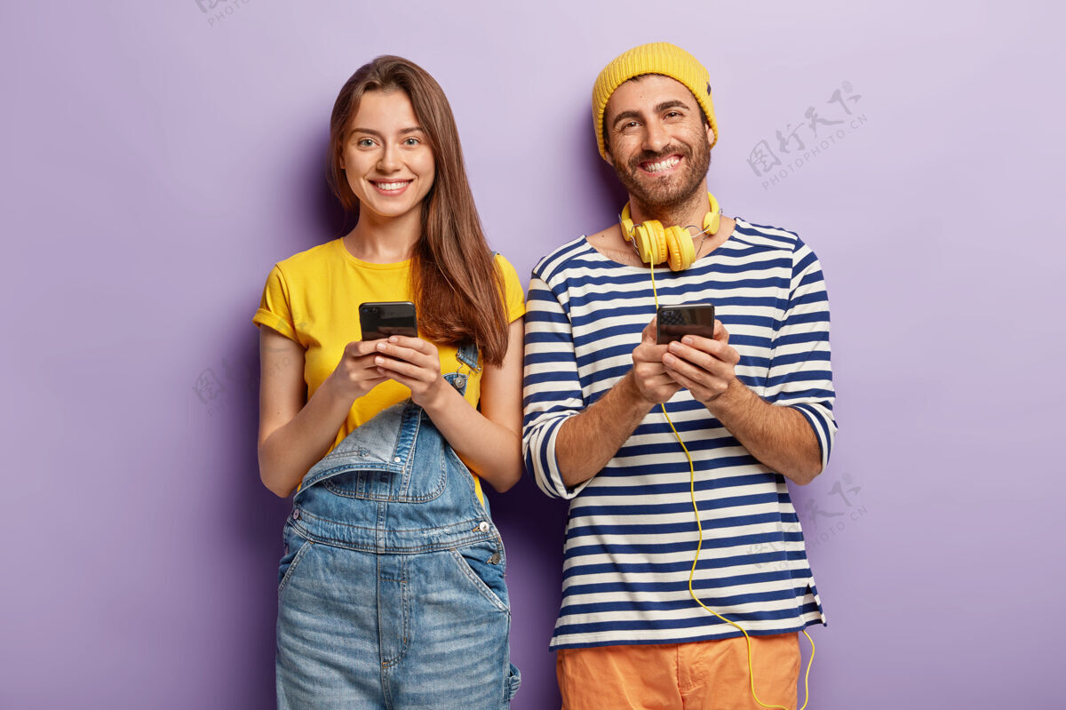 使用两个智能手机极客使用现代技术在社交网络上发布新照片的照片积极男朋友手机