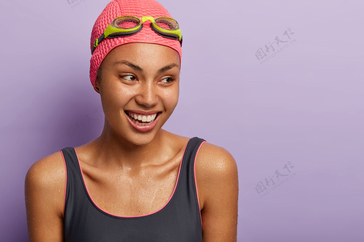 满意积极微笑的深色皮肤女子游泳运动员 准备比赛 潜水后全身湿透 身着游泳服 戴泳帽和护目镜 注意力集中 有运动的身体娱乐和爱好教练潮湿快乐