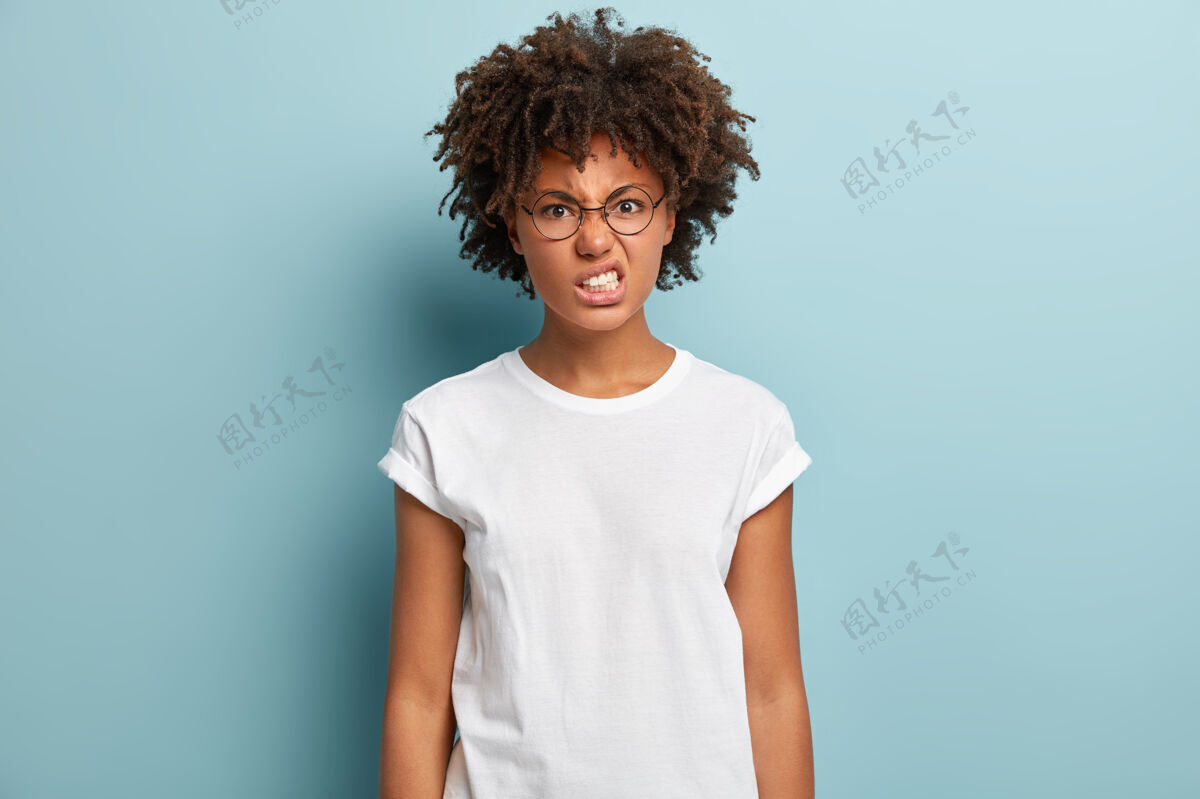 非洲恼怒的女人有着非洲式的发型 愤怒的咬牙切齿 仇恨的凝视 皱眉的脸微笑卷发不高兴