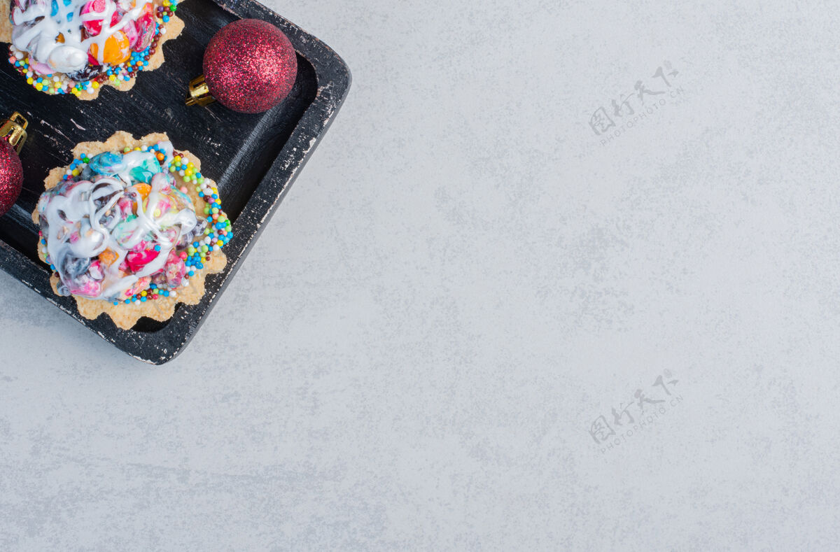 小吃在大理石表面的黑色托盘里放着圣诞饰品和糖果蛋糕甜点美味糖果