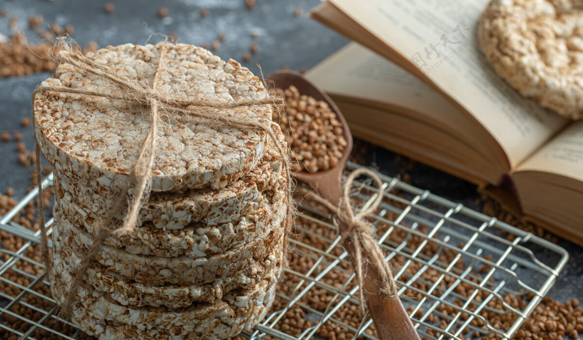 绳子一堆酥皮面包 荞麦和书放在大理石表面谷物好吃的饼干