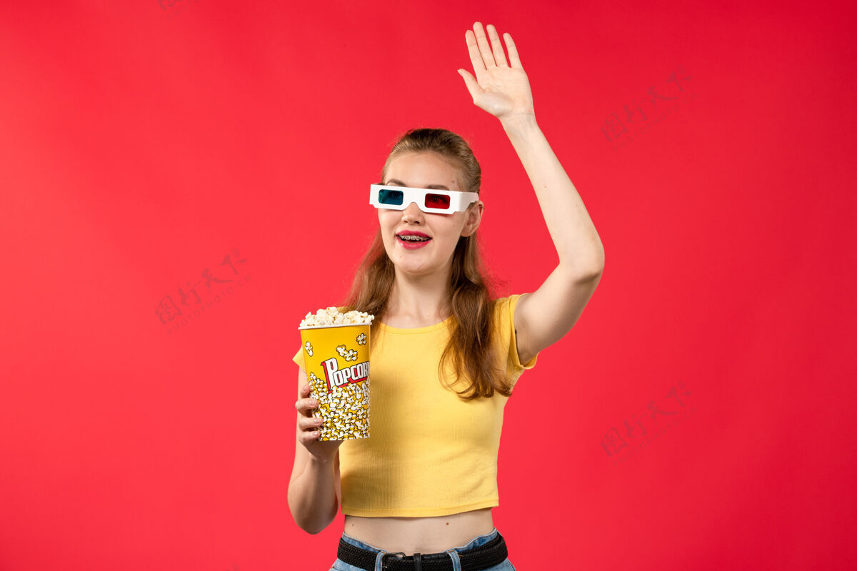 电影院正面图年轻女性在电影院拿着爆米花包在d太阳镜上看红墙电影成人电影年轻女性