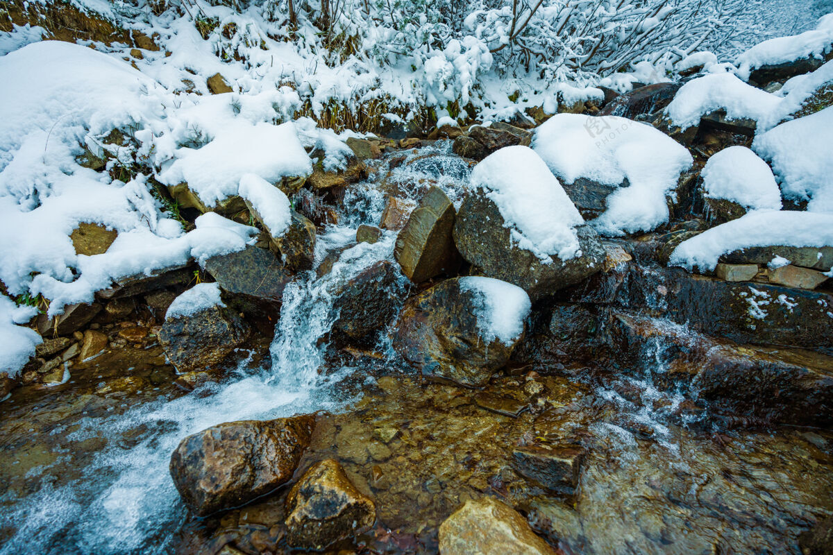 河流在美丽的乌克兰风景如画的喀尔巴阡山脉中 在潮湿的小石头和冰冷的白雪之间 有一条小溪湍急流淌 还有它奇妙的自然雪花优雅慢动作
