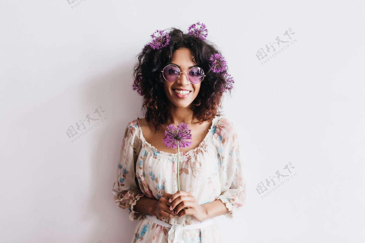 卷发笑容可掬的非洲女孩 黑色头发 紫色花朵 迷人的卷发女士 戴着太阳镜 手里拿着葱葱正面美国黑人