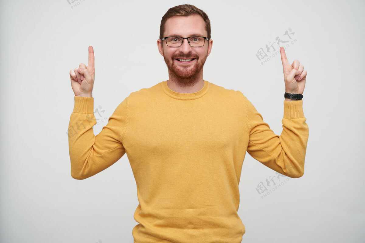 30多岁一幅快乐的年轻黑发胡子男人的画像 他戴着眼镜 食指向上 面带微笑 穿着芥末套头衫穿着好男人
