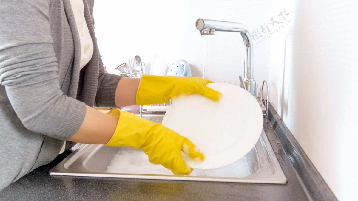 家用你这个戴着橡胶手套的家庭主妇在厨房的水槽里洗碗玻璃海绵日常