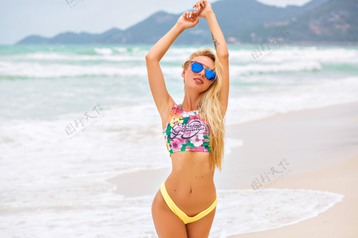 放松戴着墨镜微笑的金发女孩在海上摆姿势放松金发配件