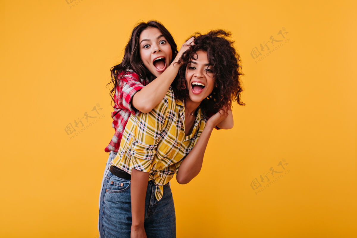 俏皮疯狂情绪化的女孩们正在玩乐女人笑着玩着她的混血女朋友的头发豆豆美丽开朗
