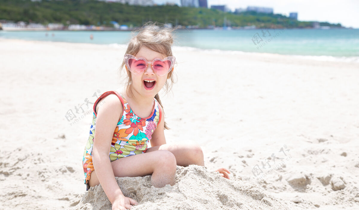 夏天一个戴眼镜的小女孩正在海边的沙滩上玩女孩时尚童年