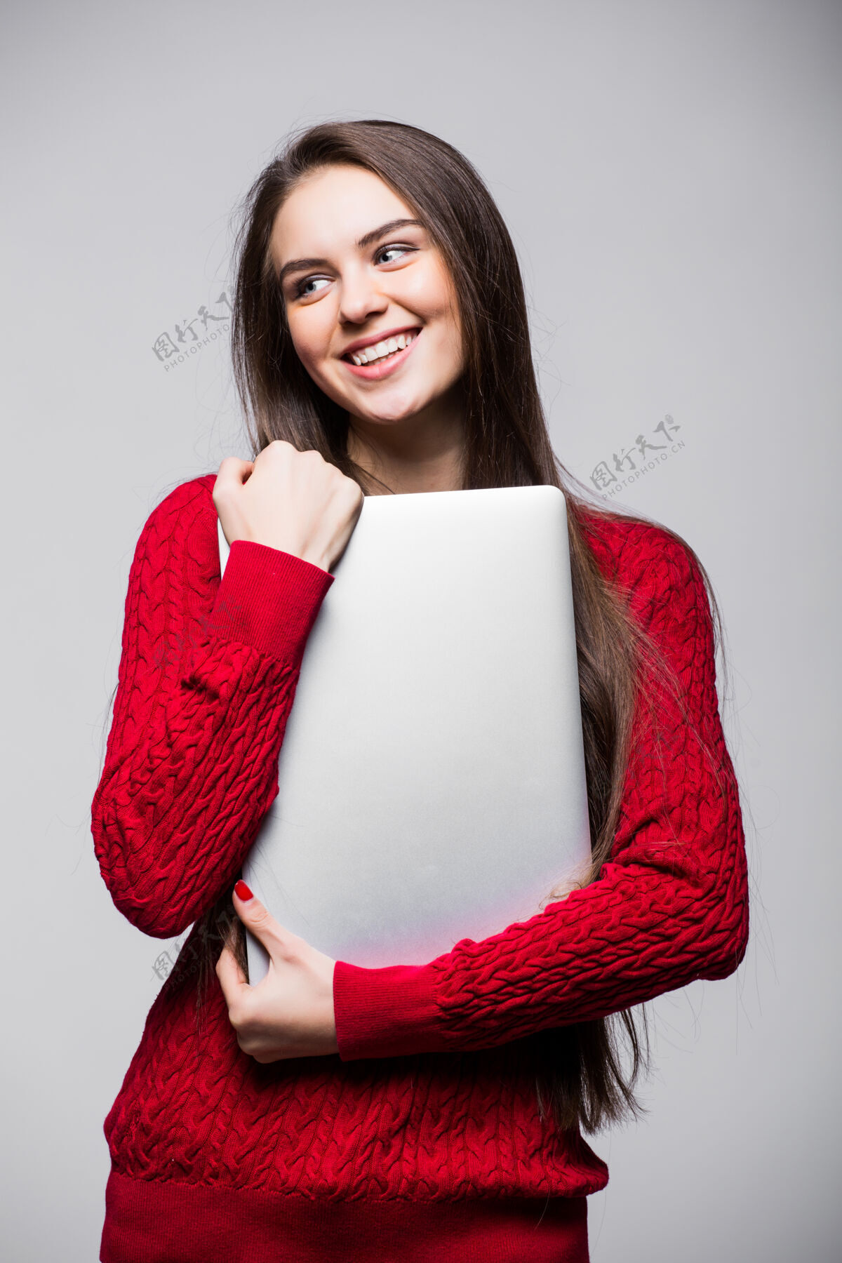 笔记本电脑年轻女子站着拿着笔记本电脑快乐的年轻女孩在用她的笔记本电脑 隔离在白色的墙上微笑黑发个人电脑