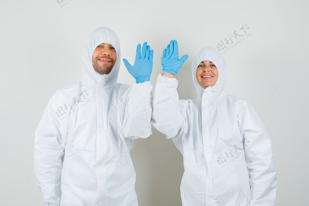 两个两个穿着防护服的医生挥手致意女人男性诊所