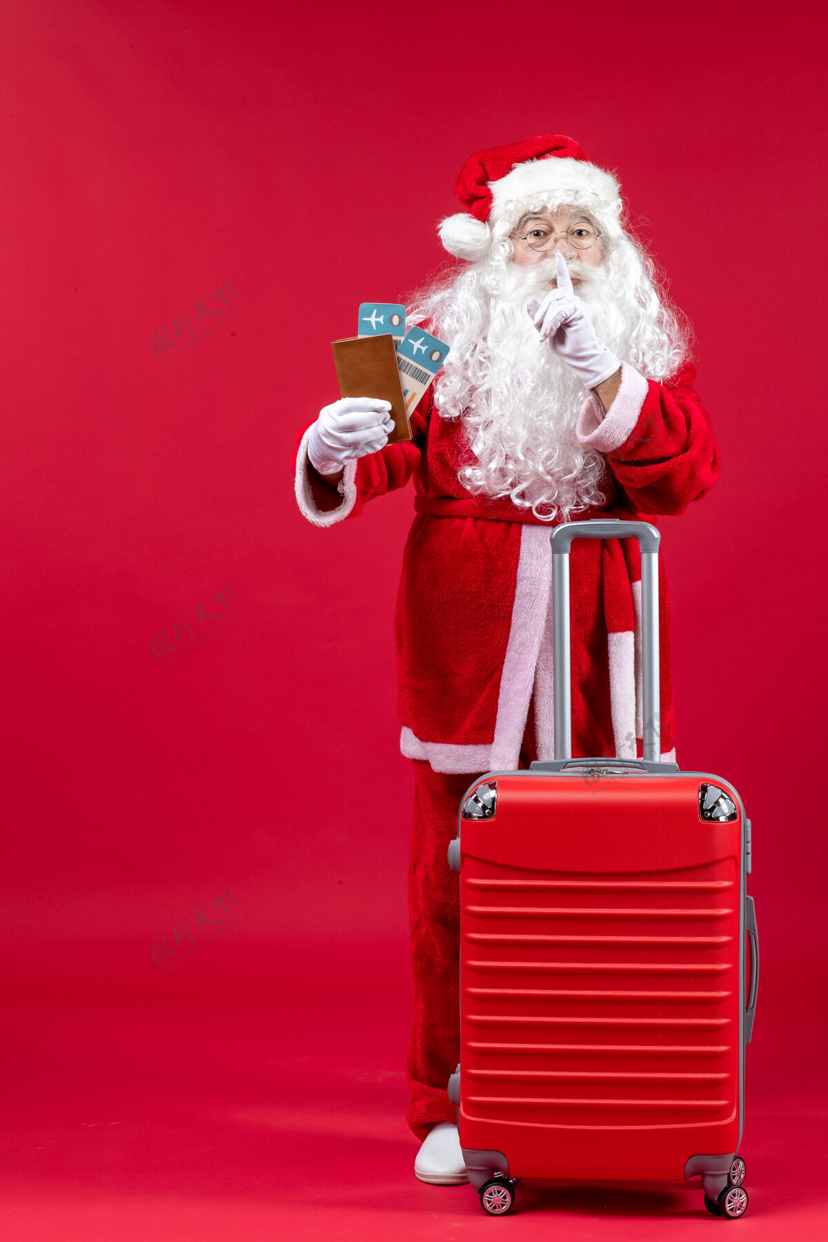圣诞老人圣诞老人的前视图 带着包 拿着票 准备在红墙上旅行人们前面快乐