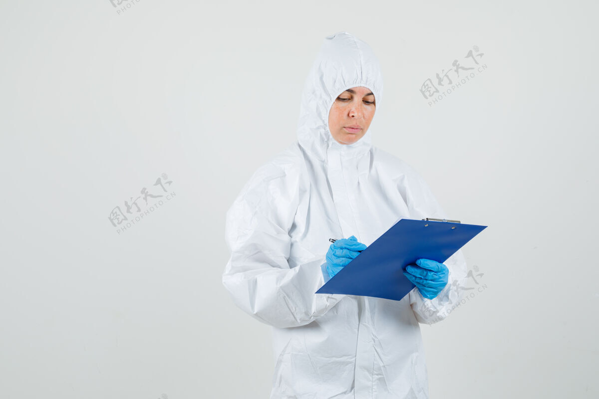 站立女医生穿着防护服在剪贴板上做笔记年轻女性医院