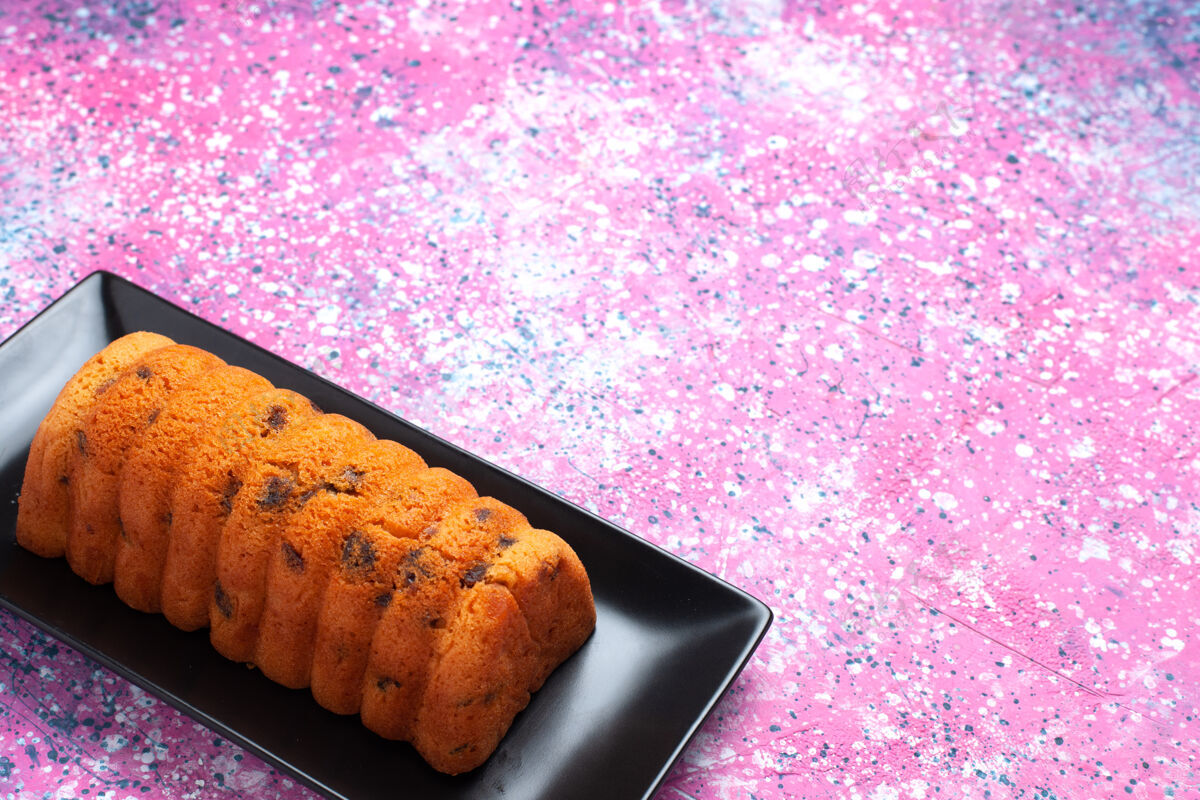 粉色正面是粉红色桌子上的黑色蛋糕锅里美味的烤蛋糕面包棕色烘焙