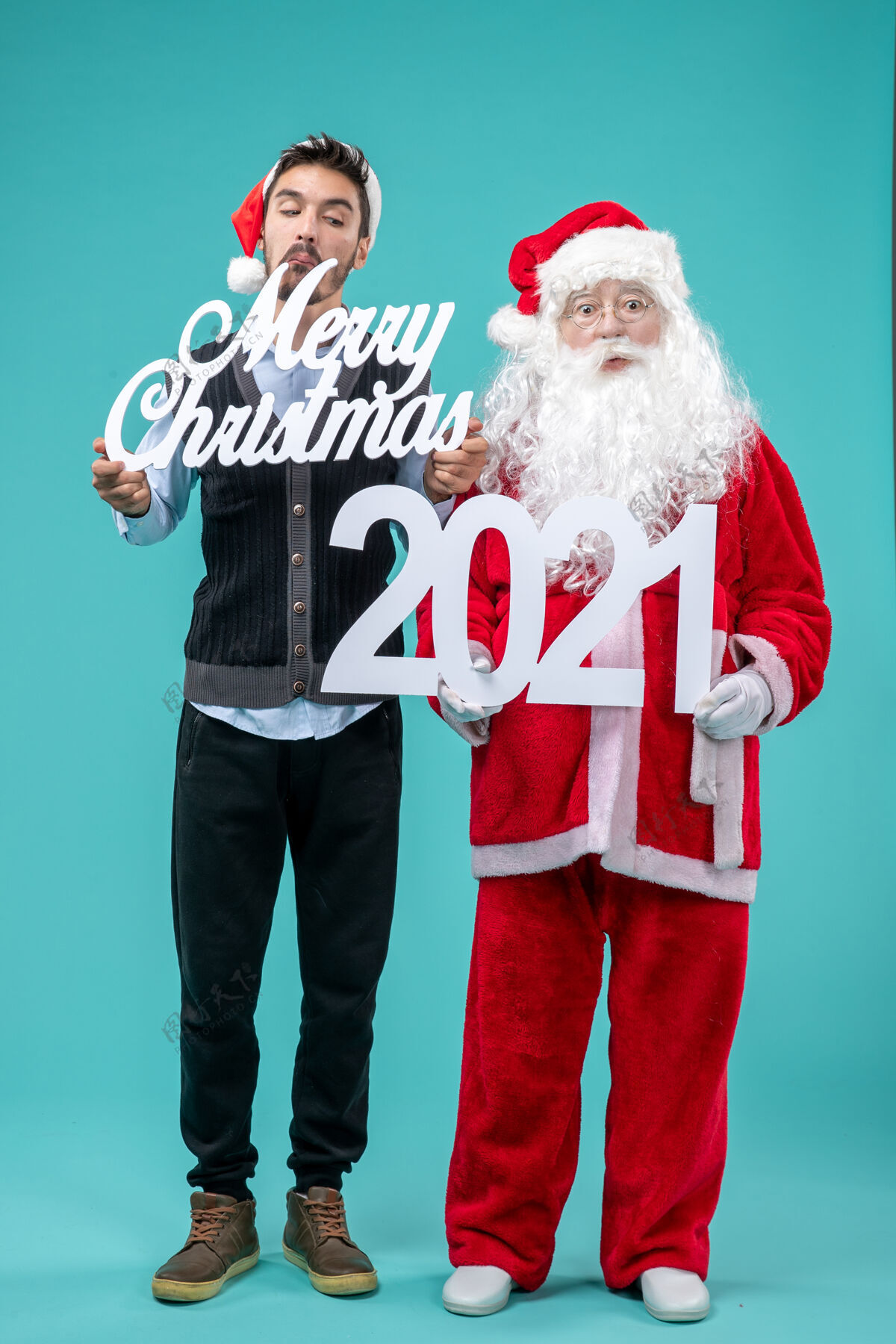 年前视图圣诞老人与年轻的男性举行圣诞快乐和蓝色背景上的作品新新年男