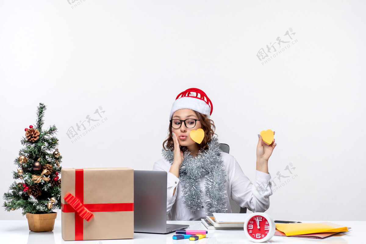 办公室正面图：年轻的女工坐在她的位置前 拿着白色背景的贴纸前面商务白色