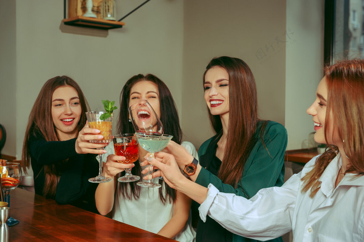 水果女朋友们在酒吧喝酒 她们坐在一张摆着鸡尾酒的木桌旁 她们在碰杯碰杯白天鸡尾酒