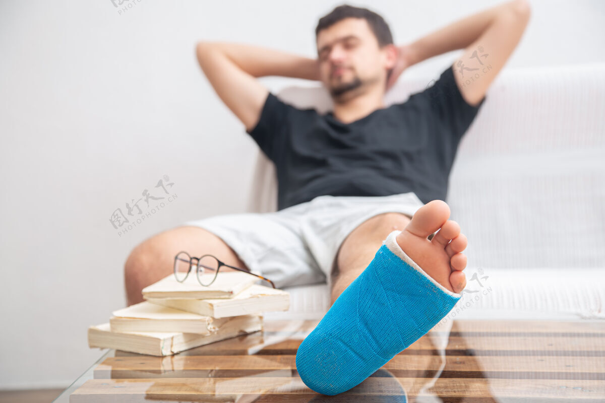 恢复男子腿部骨折用蓝色夹板治疗脚踝扭伤伤在家看书康复腿骨折绷带