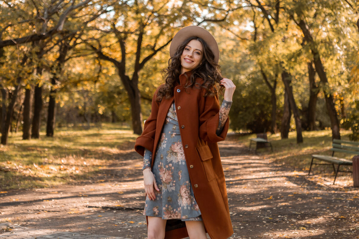 连衣裙迷人时尚微笑的女士 卷发漫步公园 身着印花连衣裙和保暖外套 秋季时尚 街头风格户外装束时尚