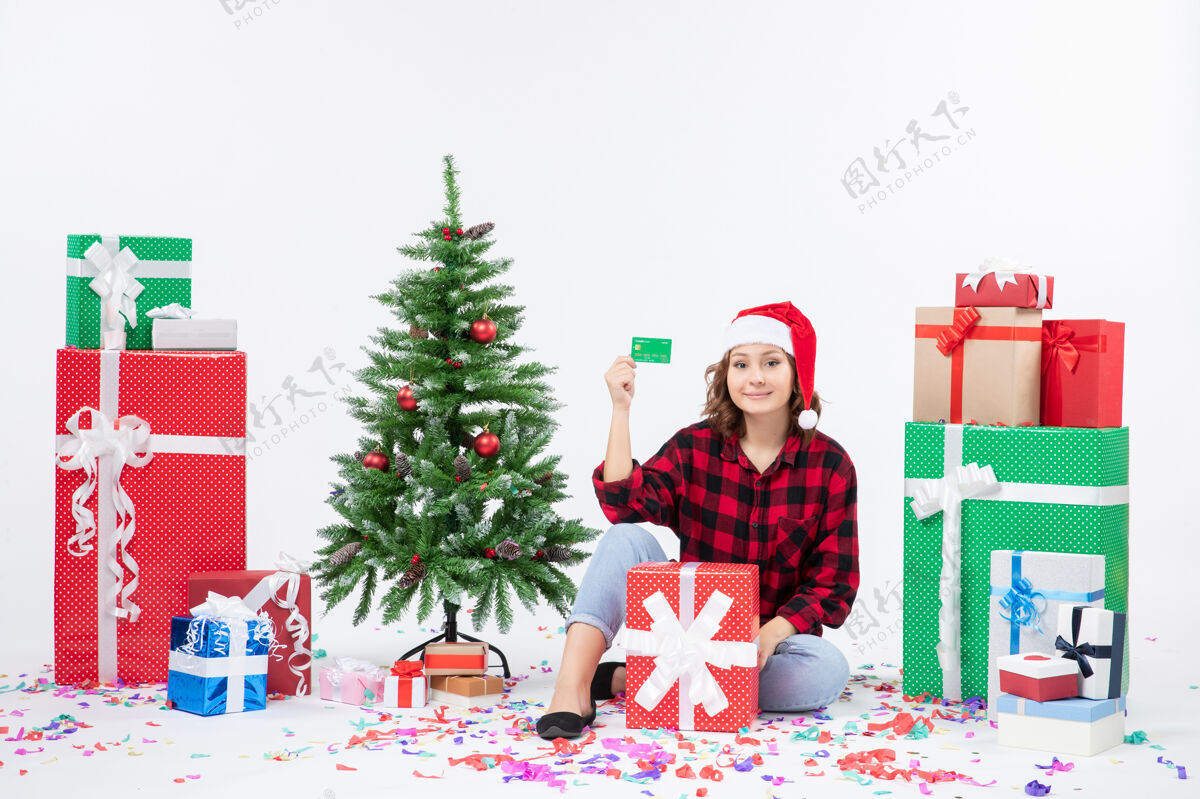 礼物正面图：年轻女子围坐在白墙上 手里拿着绿色的银行卡十二月前面圣诞节