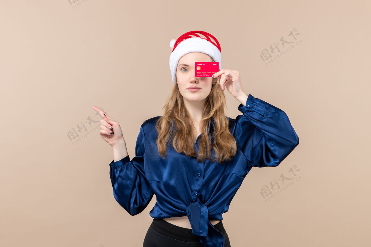 照片正面图年轻女性手持红色银行卡上粉色背景节日圣诞钱照片新年感慨圣诞节情感微笑