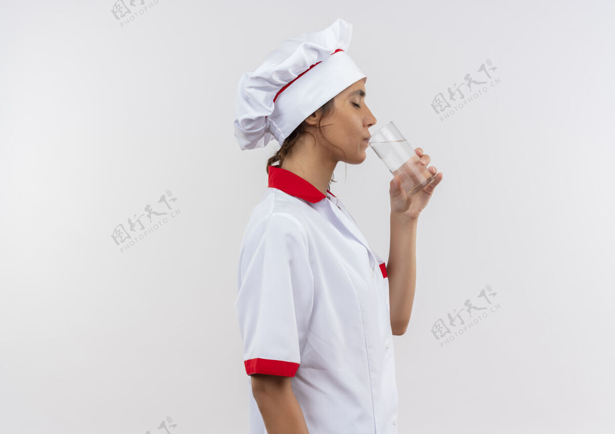厨师站在剖面图年轻的女厨师穿着厨师制服饮用水从玻璃复制空间厨师玻璃女性