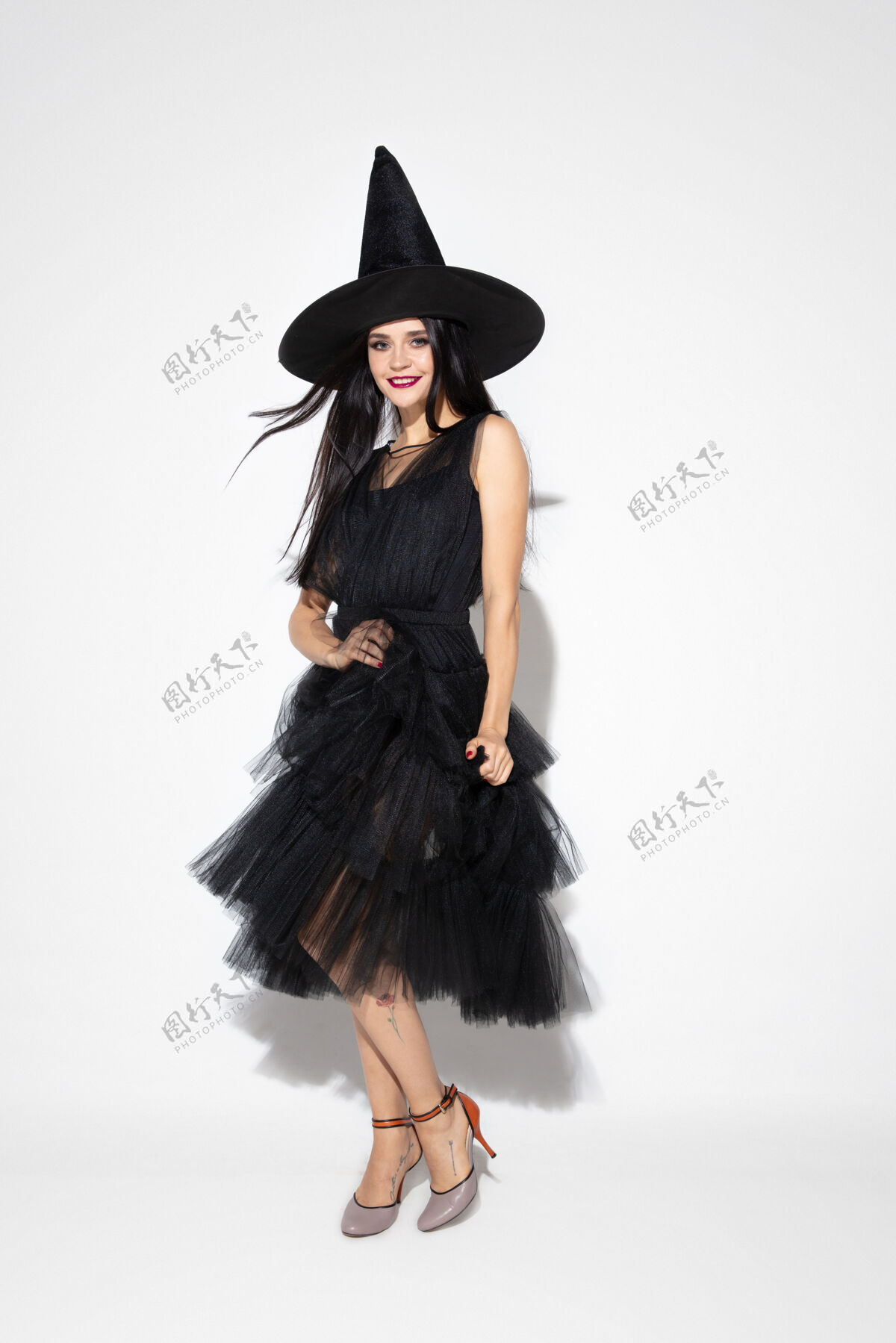性感年轻的黑发女子 戴着黑帽子 穿着白色背景的服装迷人的白人女模特万圣节 黑色星期五 网络星期一 销售 秋季概念广告空间跳舞 摆姿势促销杰克帽子