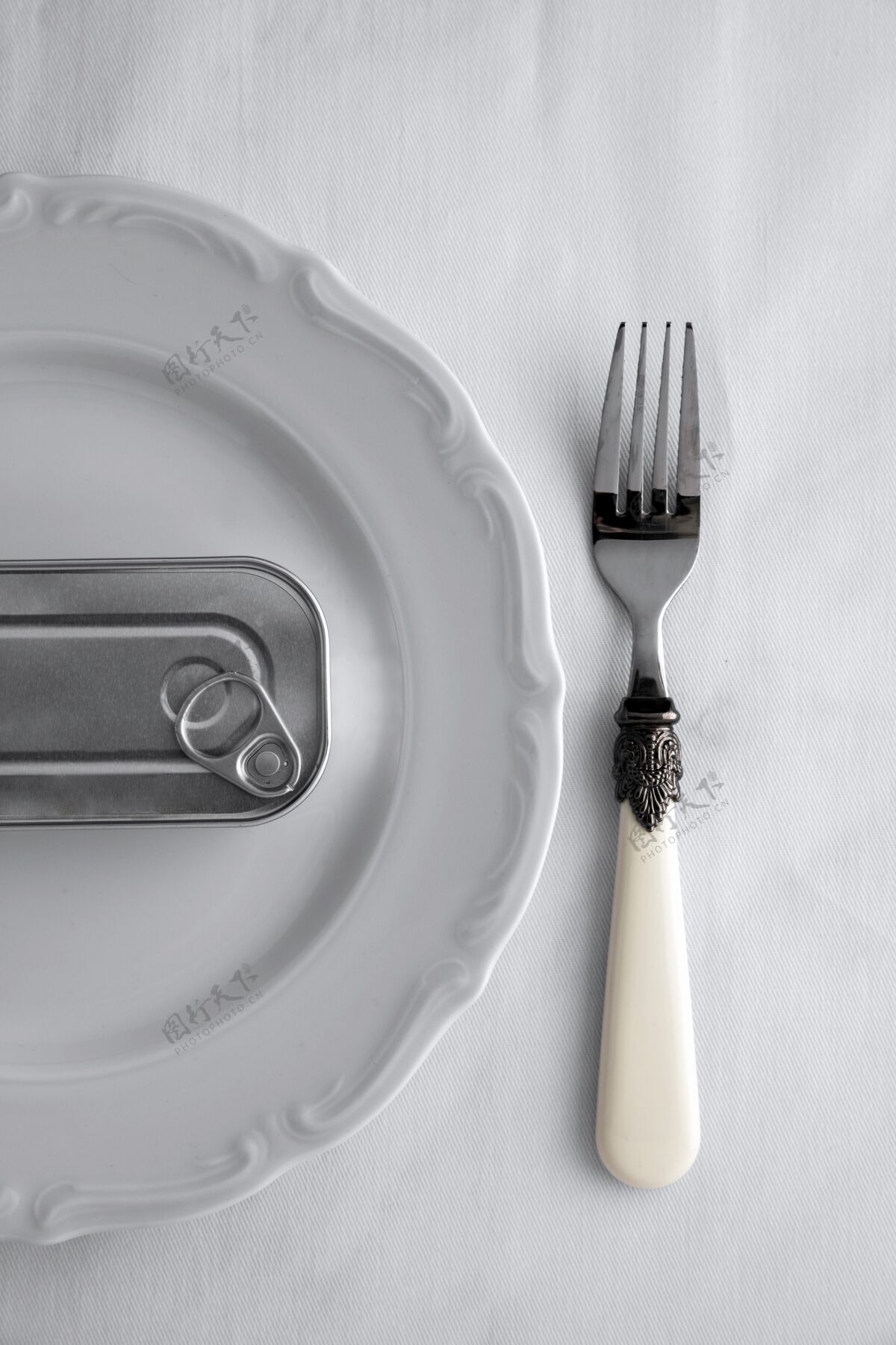 金属顶视图铁皮罐放在带叉子的盘子上保存钢锡