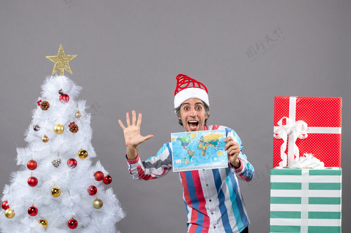 手势正面图快乐男子戴螺旋弹簧圣诞帽做高五手势手持世界地图五举行帽子