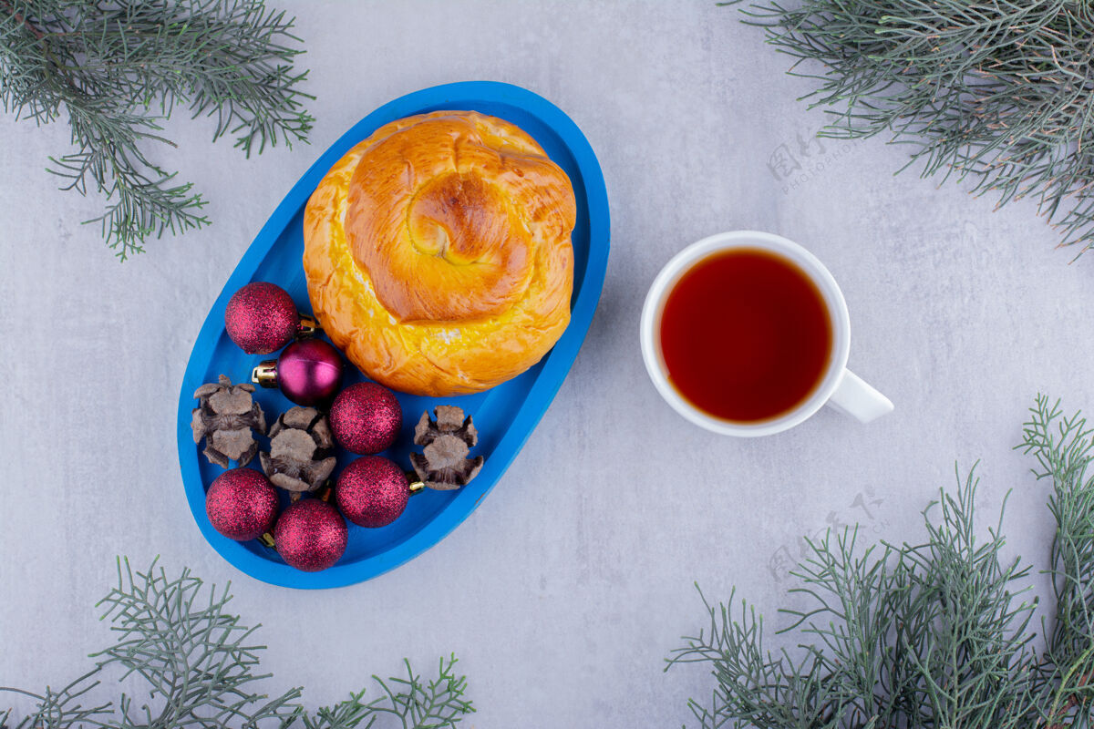 美味一杯热茶 旁边放着一盘甜面包和白色背景上的圣诞装饰品茶美味甜的