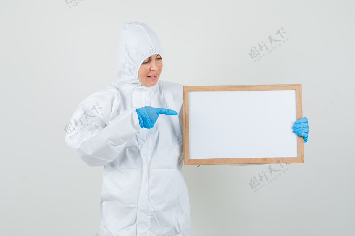 制服女医生指着穿着防护服 戴着手套的空白镜框 看上去很开心专业人员药品