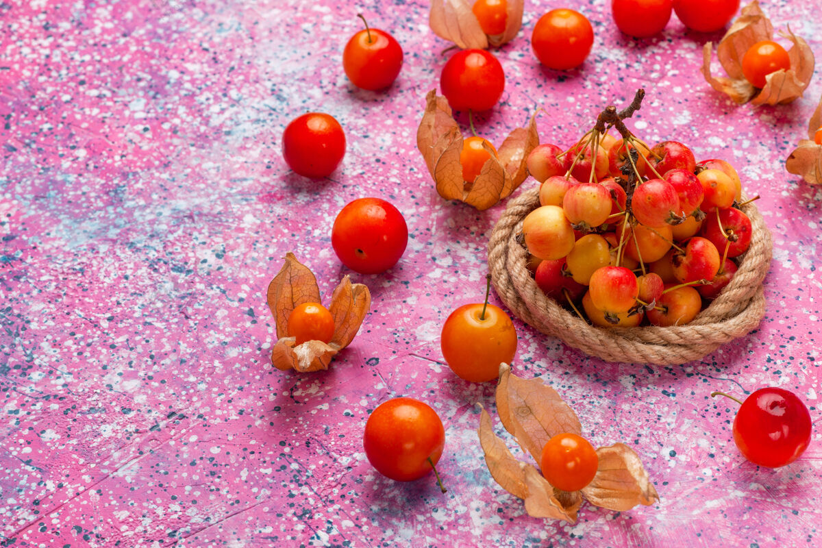 水果在浅粉色的桌子上可以看到新鲜的甜樱桃和李子食物前面樱桃